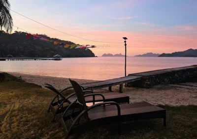 Peaceful sunset on the private beach at DK2 Resort in El Nido, Palawan. Two empty loungers face the pink sea.