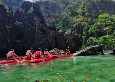 Group of kayakers exploring a turquoise lagoon surrounded by stunning limestone cliffs and lush greenery in El Nido, Palawan