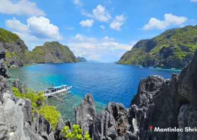 Panoramic view of a secluded limestone bay in El Nido. Shows a private boat and turquoise waters, a key highlight of Island Hopping Tour C.