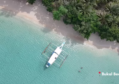 Aerial view of a private boat on a pristine beach during a Malampaya Sound tour. Crowd-free excursions in El Nido - Taytay.