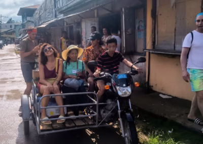 Resort guests laughing and enjoying the local tricycle ride towards the village.